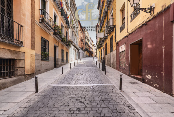 Narrow cobblestone street flanked by colorful façades with balconies and iron railings.